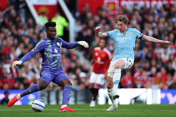 MANCHESTER, ENGLAND - APRIL 06: Andre Onana of Manchester United clears the ball under pressure from Kevin De Bruyne of Manchester City during the Premier League match between Manchester United FC and Manchester City FC at Old Trafford on April 06, 2025 in Manchester, England. (Photo by Michael Steele/Getty Images)